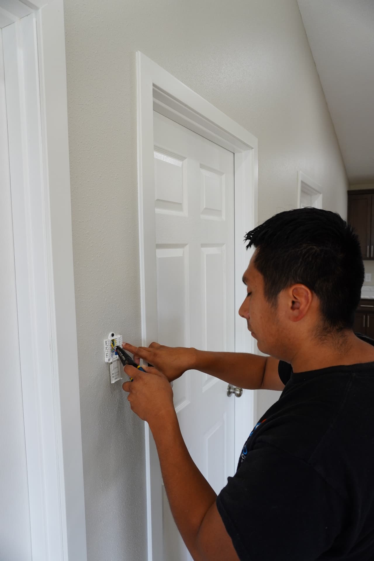 Bruno HVAC technician installing a thermostat inside a home